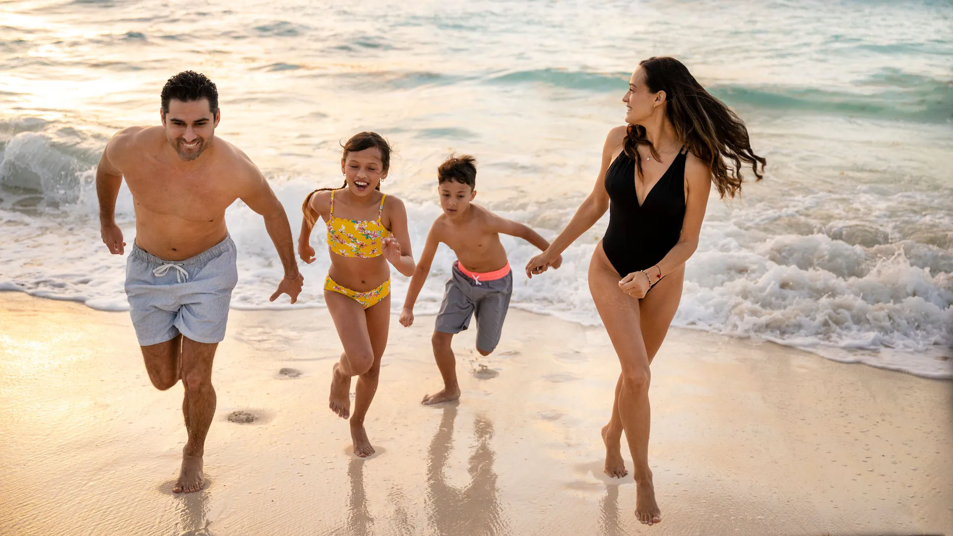 Family running along the beach at Sunscape Cancun Resort & Spa during a fun Cancun vacation.