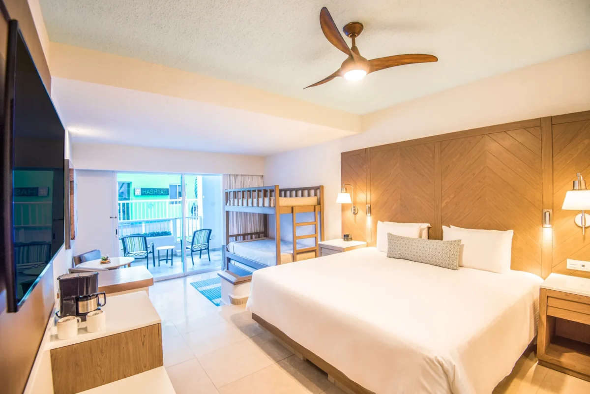 Family Junior Suite with king bed, bunk beds, and balcony at Sunscape Cancun Resort & Spa.
